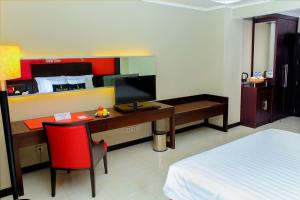 a bedroom with a desk with a computer and a bed at Zurich Hotel Balikpapan in Balikpapan