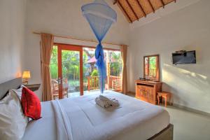 a bedroom with a large white bed and a window at Saren Villa in Nusa Penida