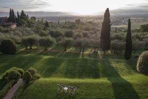 a view of a lawn with two chairs and trees at Fontelunga Hotel & Villas in Pozzo