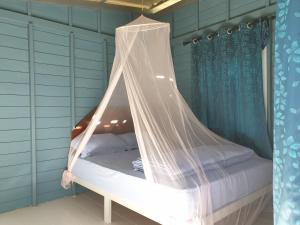 a bed with a mosquito net in a room at Baan Suan Coconut Ko Yao Noi in Ko Yao Noi