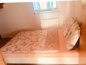 Bett in einem kleinen Zimmer mit Fenster in der Unterkunft Apartment Doderovic in Kostrena