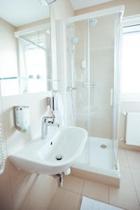 a white bathroom with a sink and a shower at Kultur- und Sportvereinigung der Wiener Gemeindebediensteten in Vienna