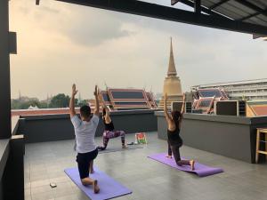 a group of people doing yoga on the roof of a building at Feung Nakorn Balcony Rooms and Cafe in Bangkok
