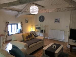 a living room with a couch and a tv at The Stable Loft, Llwynhelig Manor in Llandeilo