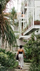 Una mujer caminando por un jardín en Rimbun Canggu Hotel, en Canggu