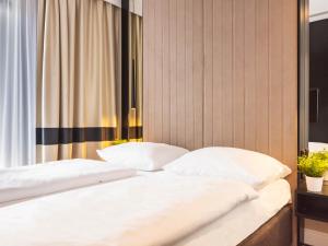 łóżko z 2 białymi poduszkami w pokoju w obiekcie VacationClub – Baltic Park Fort Apartament F.308 w Świnoujściu +12 zdjęć