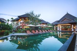 ośrodek z basenem z leżakami i parasolami w obiekcie Rama Phala Resort & Spa w mieście Ubud