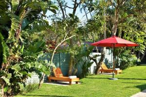 two benches and a red umbrella in a yard at La Perle in Ballito