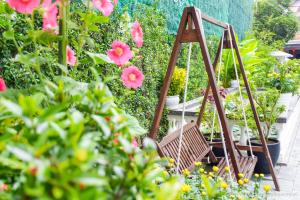 a swing in a garden with pink flowers at Hoi An Rosemary Boutique Hotel & Spa in Hoi An