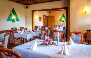 un restaurante con mesas blancas y sillas con flores. en Ferienhotel Augustusburg, en Augustusburg