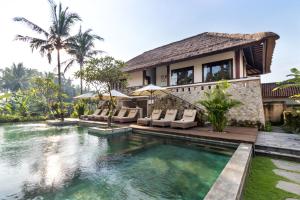 a villa with a swimming pool and a house at Radha Phala Resort & Spa in Ubud
