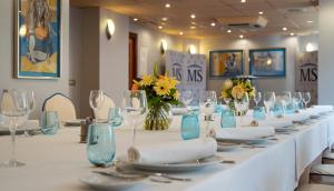 a long white table with glasses and plates and flowers at Hotel MS Maestranza Málaga in Málaga