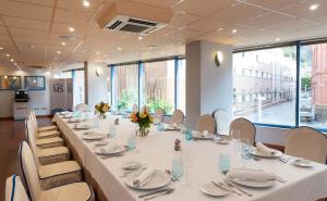 a long table in a room with white tables and chairs at Hotel MS Maestranza Málaga in Málaga