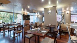 a restaurant with wooden tables and chairs and a large window at Hotel MS Maestranza Málaga in Málaga