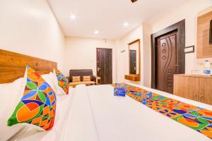 a bedroom with a white bed with colorful pillows at FabHotel Spark Inn Dwarakanagar in Vijayawāda
