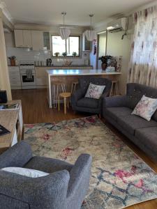 a living room with two couches and a kitchen at Magenta Cottage in Tumbarumba