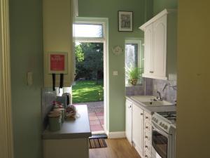 una cocina con paredes verdes y una puerta a un patio en Garden Flat, Ealing, en Ealing