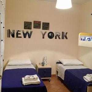 una camera con due letti e un cartello di New York sul muro di Dimora dei saraceni a Marina di Pisticci