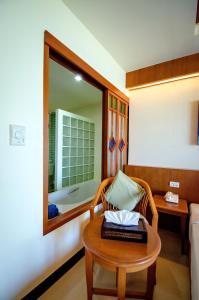 a room with a bed and a table with a mirror at Khaolak Orchid Beach Resort - SHA Extra Plus in Khao Lak