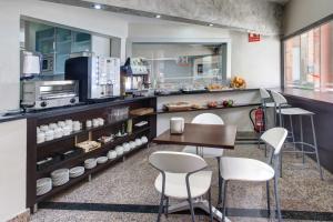 une cuisine avec des chaises blanches, une table et un comptoir dans l'établissement Hotel Nuevo Triunfo, à Barcelone