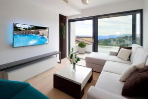 uma sala de estar com um sofá e uma televisão na parede em MODENA MARIS-heated pool-grill-relax-jacuzzi apartments em Ičići