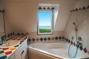 a bathroom with a tub and a sink and a window at "La Girelle, bord de mer" in Honfleur