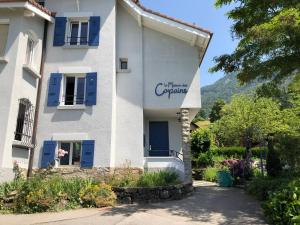 un edificio blanco con persianas azules en La Maison des Copains, en Blonay