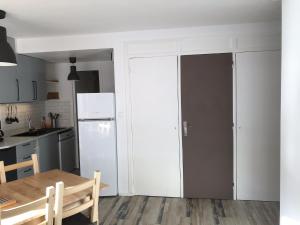eine Küche mit einem Tisch und einem weißen Kühlschrank in der Unterkunft Gite Bel Air La Mongie in La Mongie
