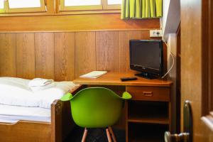 Zimmer mit einem Schreibtisch mit einem Computer und einem grünen Stuhl in der Unterkunft Guesthouse Pension Grafenstein in Meran