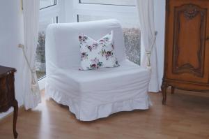 una silla blanca con una almohada en una habitación en Weingut Landmann Ferienwohnungen, en Freiburg im Breisgau
