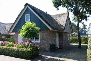 a small brick house with a black roof and flowers at Villa Lachmöwe in Sint Maartensvlotbrug
