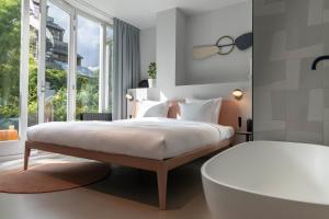 Schlafzimmer mit einem Bett mit einer Badewanne und einem Fenster in der Unterkunft Conscious Hotel Museum Square in Amsterdam