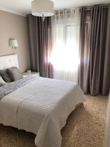 um quarto com uma cama branca e uma janela em Apartamento Parque 2 Playa de Gandía em Playa de Gandia