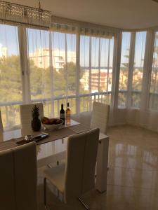 una sala da pranzo con tavolo, sedie e finestre di Apartamento Parque 2 Playa de Gandía a Playa de Gandia