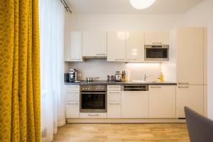 ウィーンにあるヴィエナ グランド アパートメンツ シティの白い家電製品と黄色いカーテン付きのキッチン