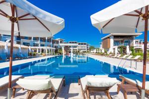a pool at a resort with chairs and umbrellas at Apolonia Resort in Sozopol