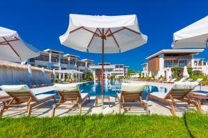 a pool at a resort with chairs and an umbrella at Apolonia Resort in Sozopol