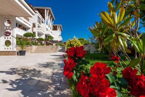a row of red flowers in front of a building at Apolonia Resort in Sozopol