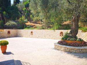 a courtyard with a tree and a stone wall at Nikoli Apartments in Benitses