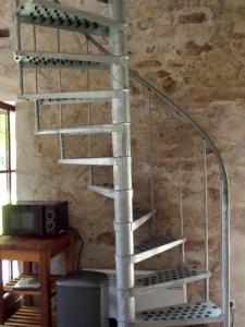 a metal spiral staircase in a room with a television at Domaine Pouzoult, gîte l'Escalier in Sazeray