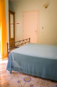a bedroom with a bed with a blue blanket on it at Hotel Cala del Citro in Maratea