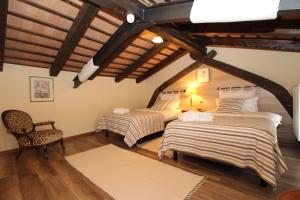 Cette chambre mansardée comprend deux lits et une chaise. dans l'établissement Casa Bandel, à Komen