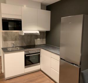 a kitchen with white cabinets and a stainless steel refrigerator at Stryn House - Hotel & Apartments in Stryn