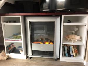 a fireplace in a book shelf with a fire in it at Beynon&Bolton’s Country Loft Escape in Katikati