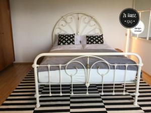 - un lit blanc dans une chambre dotée d'un tapis noir et blanc dans l'établissement Zu Hause 1949, à Markdorf