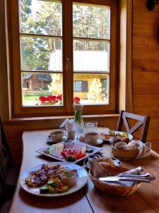 een houten tafel met borden eten erop bij Vējciems in Liepene