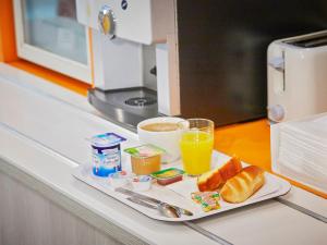 a tray with a plate of food and a glass of orange juice at Première Classe Melun Senart in Vert-Saint-Denis