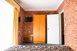 a room with a bed and a chair in it at Akuna Motor Inn and Apartments in Dubbo