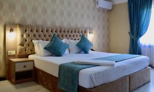 a bedroom with a large bed with blue pillows at Dostar Inn in Shymkent