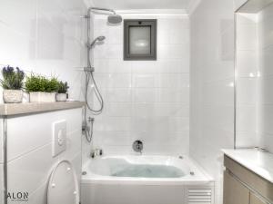 a white bathroom with a tub and a shower at אצולת הכיכר a in Safed